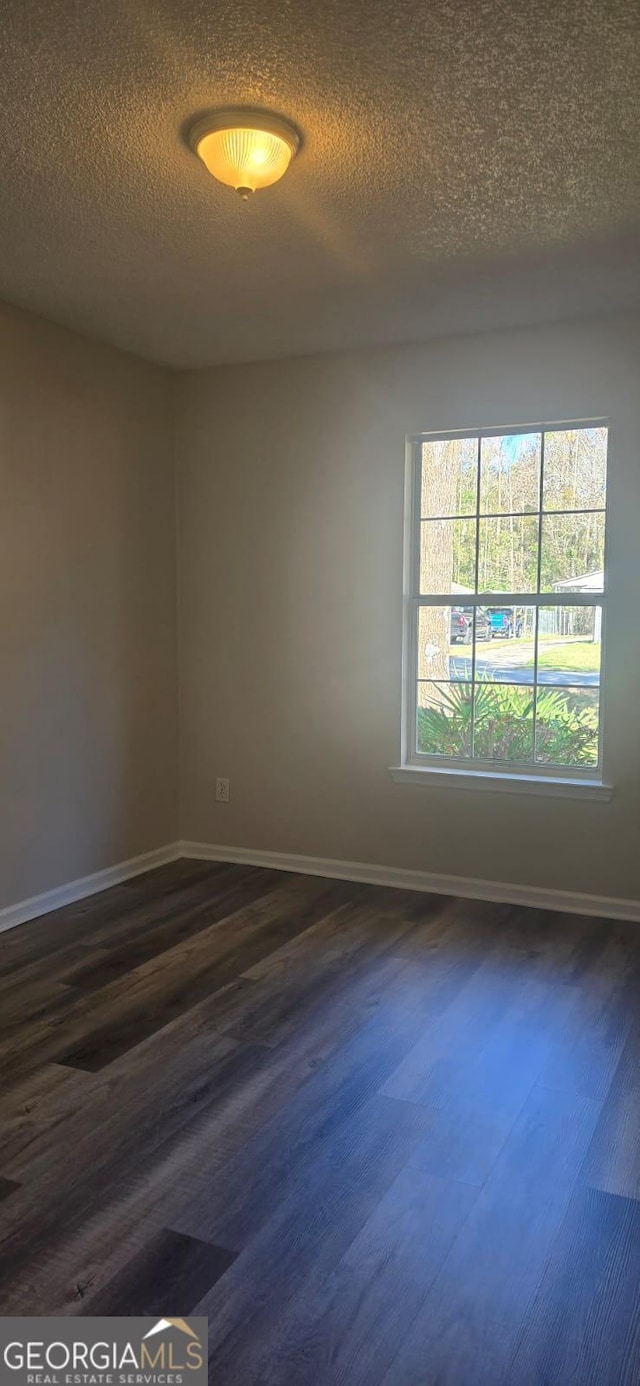 unfurnished room with a textured ceiling and dark hardwood / wood-style flooring