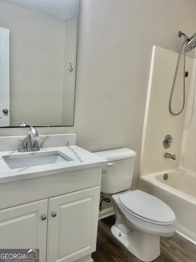 full bathroom featuring a textured ceiling, wood-type flooring, vanity, toilet, and shower / bathtub combination