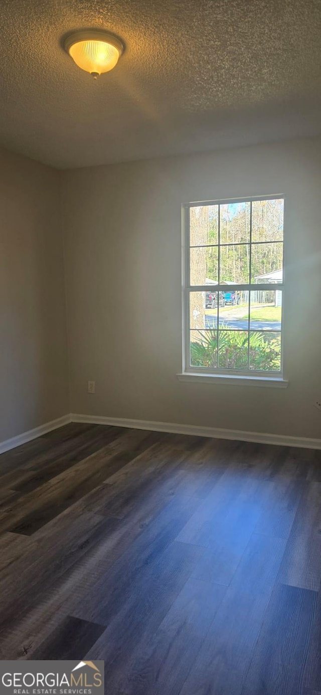 spare room with a textured ceiling and dark hardwood / wood-style floors