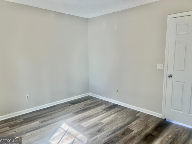 unfurnished room with dark wood-type flooring