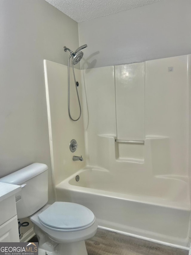 full bathroom featuring a textured ceiling, shower / bathtub combination, vanity, toilet, and hardwood / wood-style flooring