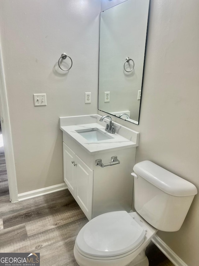 bathroom featuring toilet, vanity, and hardwood / wood-style flooring