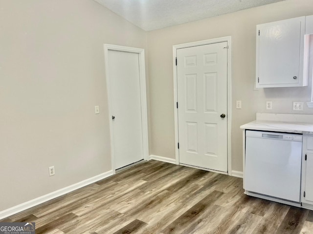 kitchen with white dishwasher, white cabinetry, light hardwood / wood-style flooring, and a textured ceiling