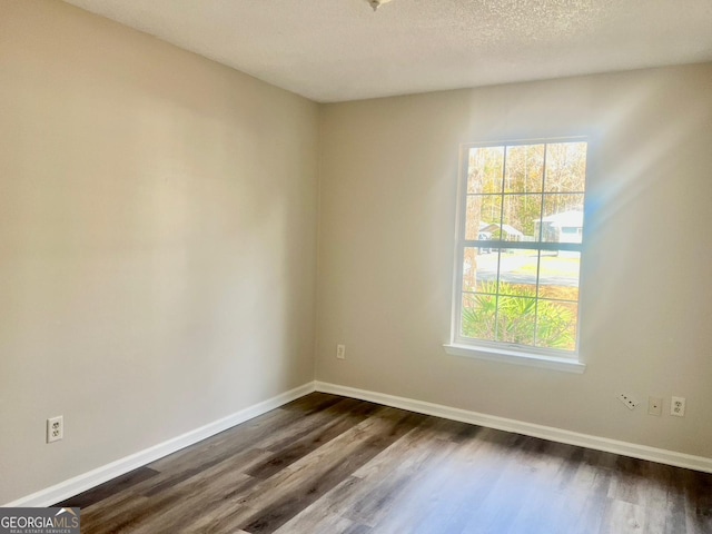 empty room with dark hardwood / wood-style floors and a textured ceiling