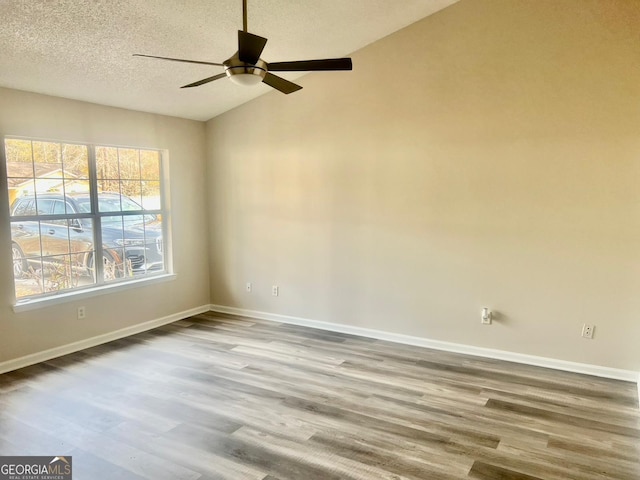 empty room featuring vaulted ceiling, ceiling fan, a textured ceiling, and wood-type flooring