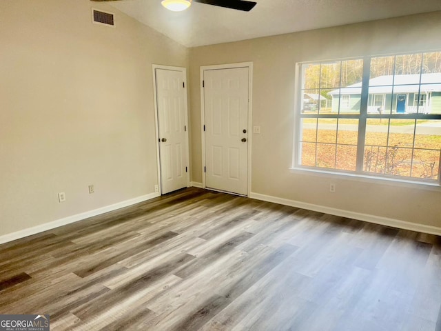 empty room featuring lofted ceiling, a healthy amount of sunlight, ceiling fan, and light hardwood / wood-style flooring