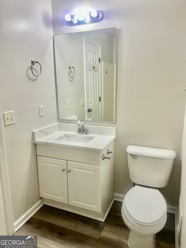 bathroom with toilet, vanity, and hardwood / wood-style floors