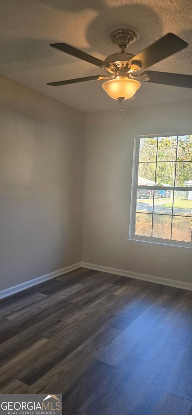 empty room featuring ceiling fan, dark hardwood / wood-style floors, and a textured ceiling