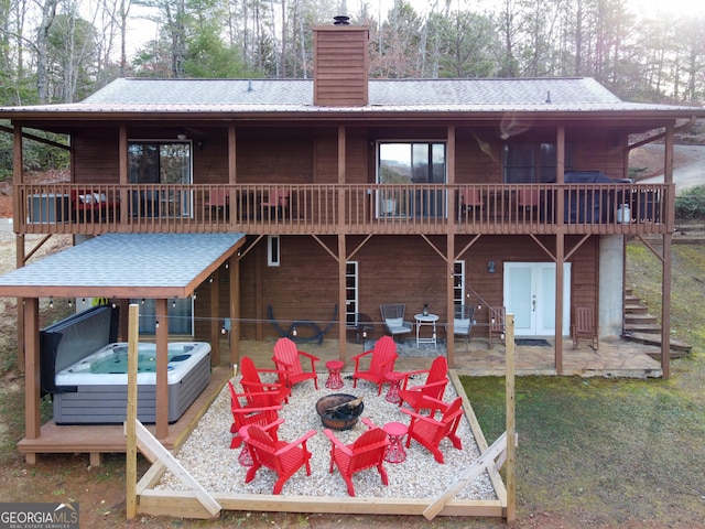 back of house featuring a hot tub, a fire pit, a patio area, and a wooden deck