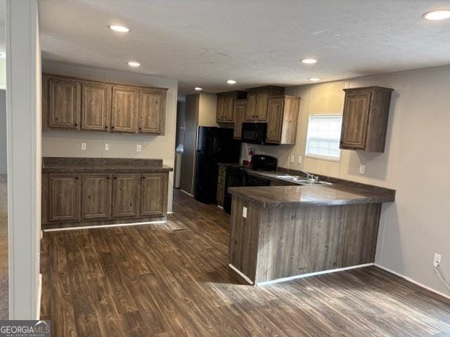 kitchen with dark hardwood / wood-style flooring, sink, black appliances, and kitchen peninsula