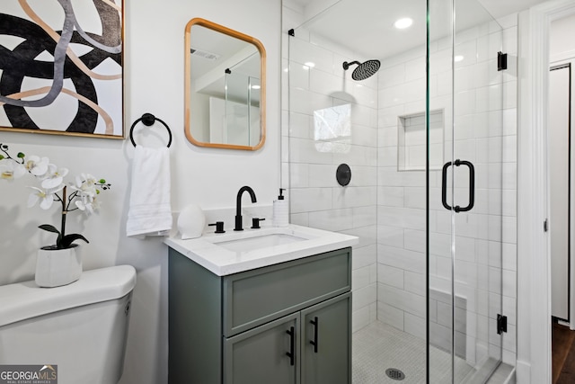 bathroom with vanity, toilet, and a shower with shower door