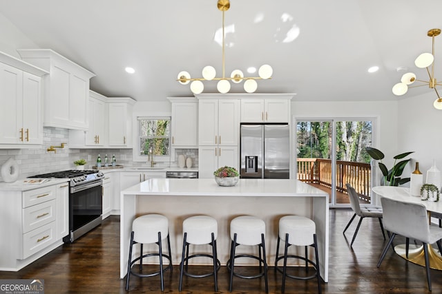 kitchen with sink, white cabinetry, a kitchen island, pendant lighting, and stainless steel appliances