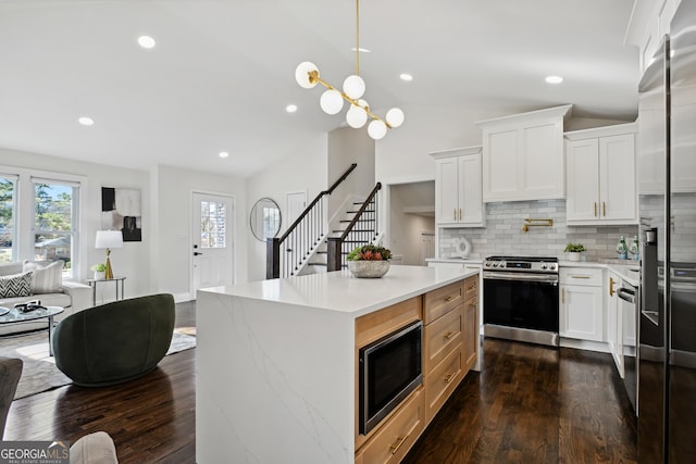 kitchen with white cabinetry, lofted ceiling, appliances with stainless steel finishes, and decorative backsplash