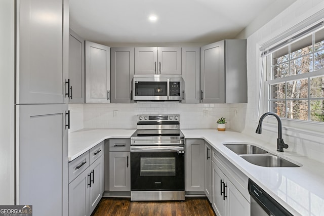 kitchen featuring gray cabinetry, backsplash, sink, light stone countertops, and stainless steel appliances