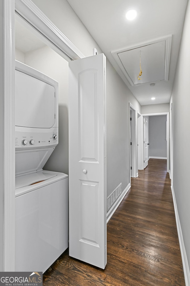 washroom with dark hardwood / wood-style flooring and stacked washing maching and dryer