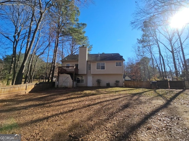 back of property with a wooden deck and a shed