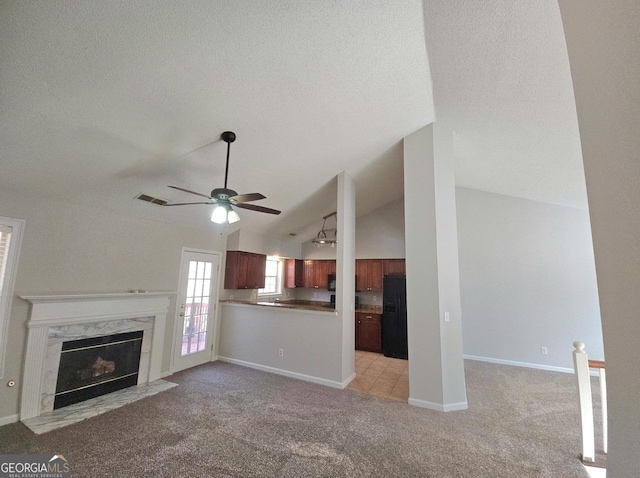 unfurnished living room with ceiling fan, a high end fireplace, light colored carpet, a textured ceiling, and vaulted ceiling