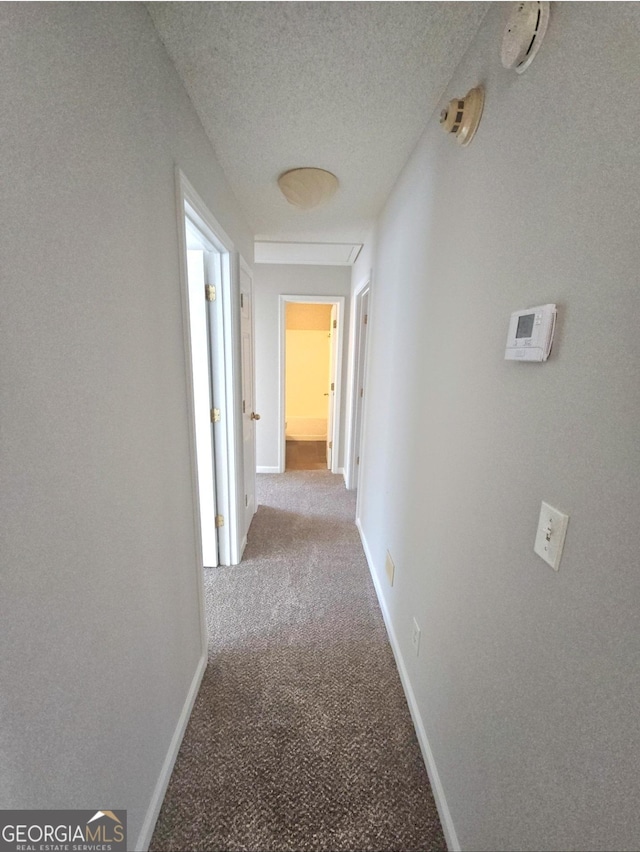 corridor featuring light colored carpet and a textured ceiling