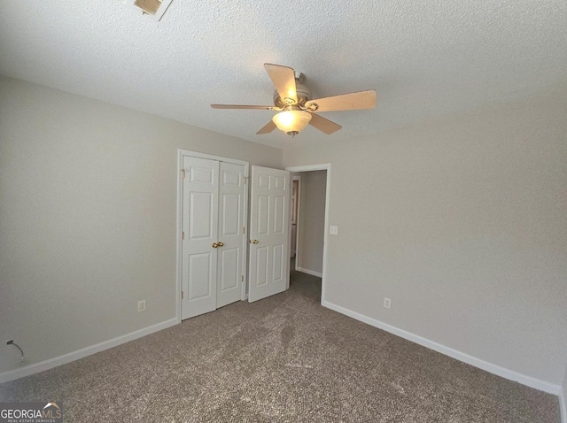 unfurnished bedroom with carpet, ceiling fan, a textured ceiling, and a closet