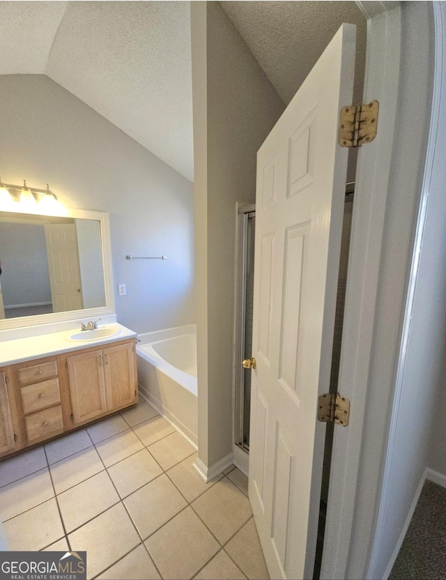 bathroom featuring tile patterned flooring, vanity, a textured ceiling, and vaulted ceiling