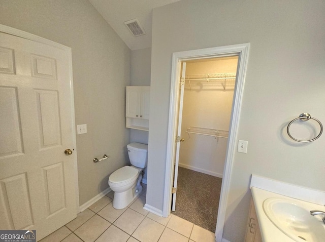 bathroom with toilet, vaulted ceiling, tile patterned floors, and sink