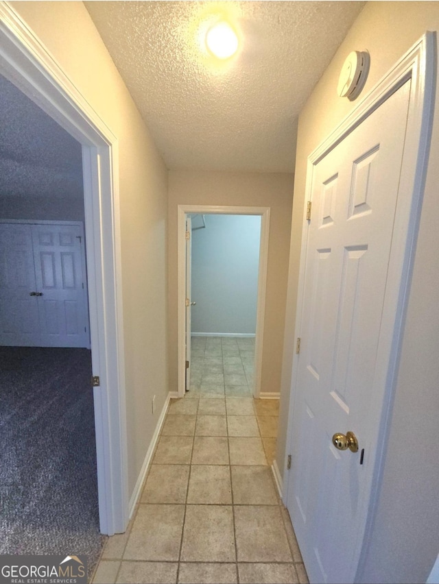 hall featuring light tile patterned floors and a textured ceiling