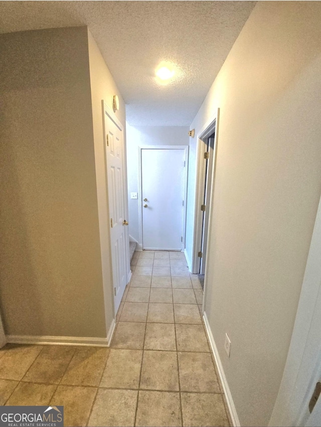 hall featuring light tile patterned floors and a textured ceiling