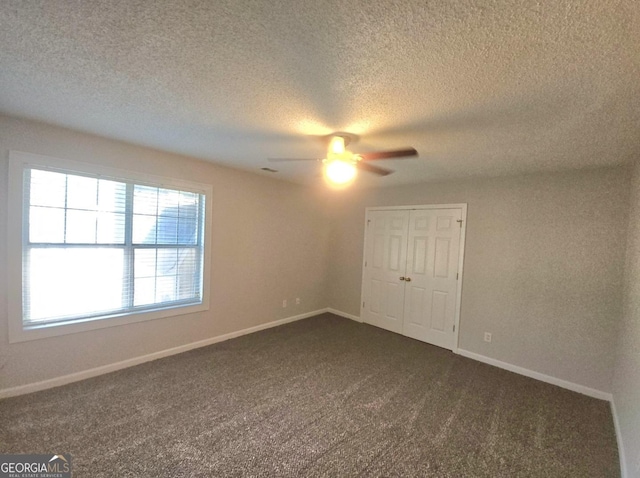 spare room featuring dark carpet and ceiling fan