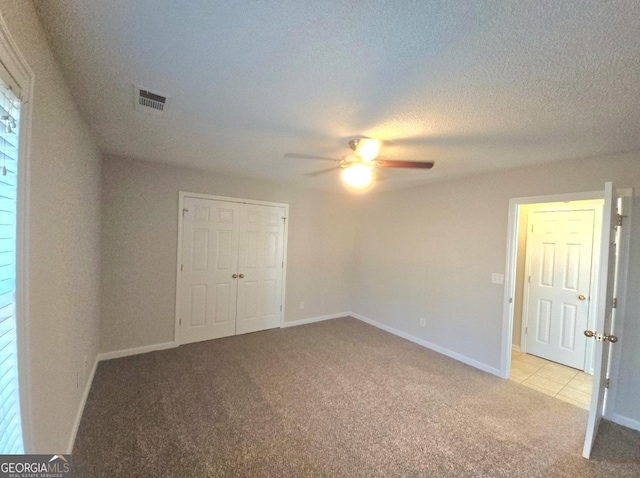 unfurnished bedroom featuring ceiling fan, light colored carpet, and a closet