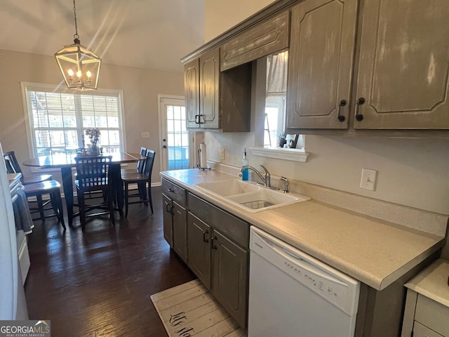 kitchen with dishwasher, sink, dark wood-type flooring, pendant lighting, and a chandelier