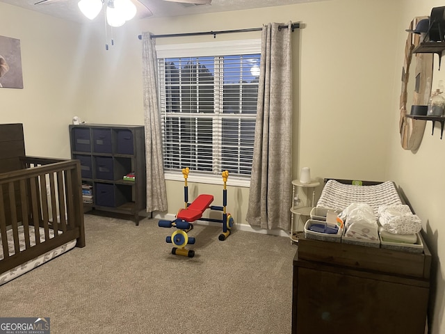 bedroom with carpet flooring, a crib, ceiling fan, and a textured ceiling