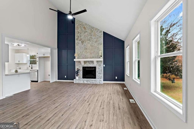 unfurnished living room featuring a fireplace, light wood-type flooring, plenty of natural light, and ceiling fan