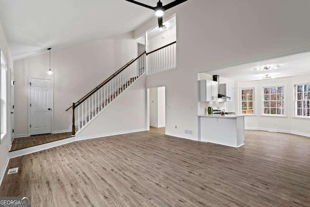 unfurnished living room featuring wood-type flooring, high vaulted ceiling, and ceiling fan