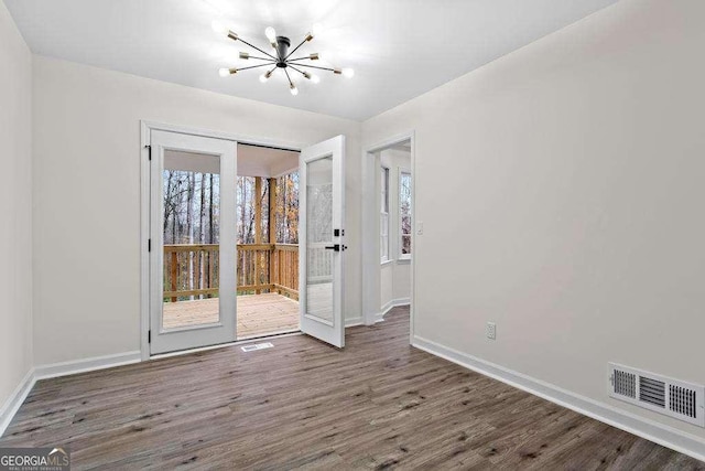 spare room with dark hardwood / wood-style flooring and an inviting chandelier