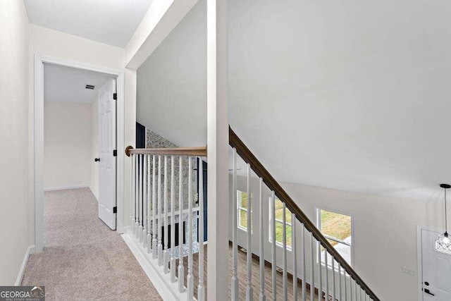 hallway featuring lofted ceiling and light carpet