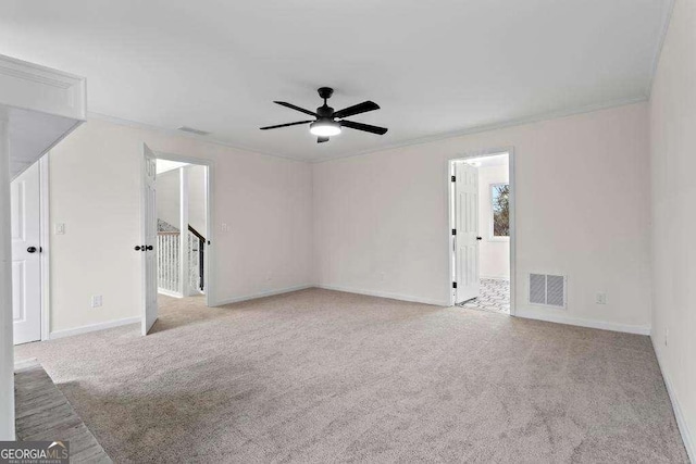 empty room featuring ceiling fan, light colored carpet, and ornamental molding