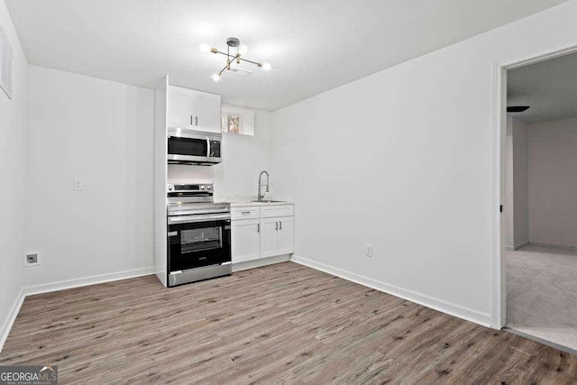 kitchen featuring appliances with stainless steel finishes, light hardwood / wood-style flooring, white cabinetry, and sink