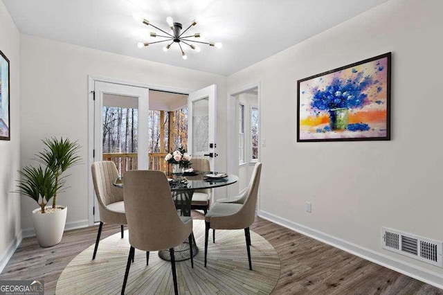 dining area with hardwood / wood-style flooring and a notable chandelier