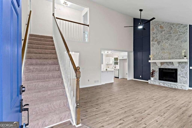 interior space with hardwood / wood-style floors, ceiling fan, a stone fireplace, and high vaulted ceiling