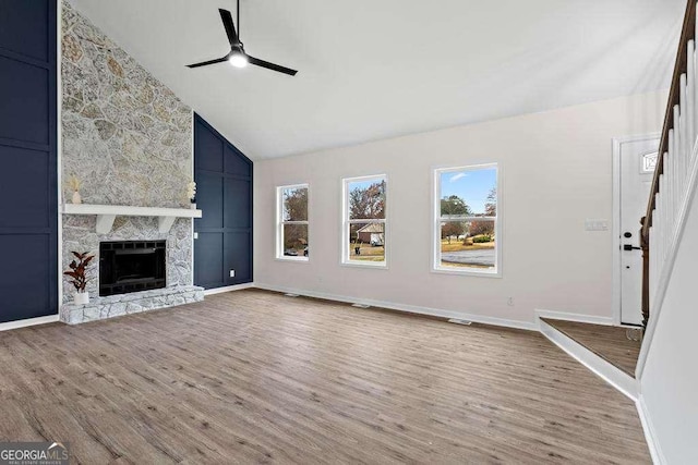 unfurnished living room featuring hardwood / wood-style flooring, ceiling fan, a fireplace, and high vaulted ceiling