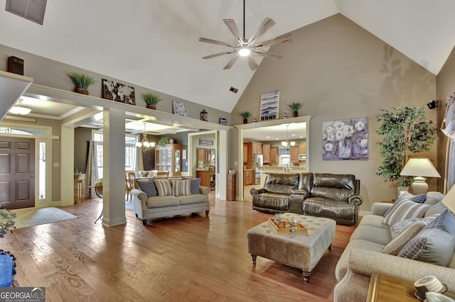 living room featuring wood-type flooring, ceiling fan with notable chandelier, and high vaulted ceiling