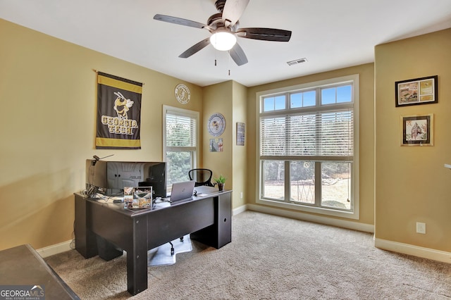 carpeted home office featuring ceiling fan