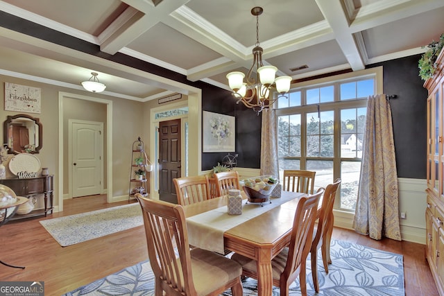 dining area featuring coffered ceiling, ornamental molding, beam ceiling, light hardwood / wood-style floors, and a chandelier