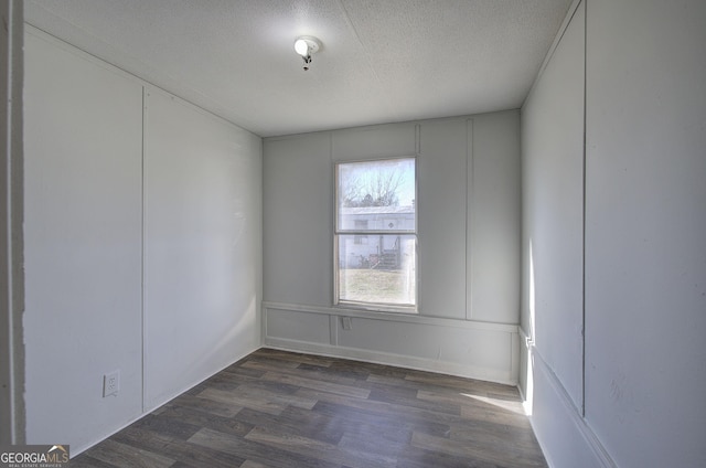 unfurnished room featuring dark wood-type flooring and a textured ceiling