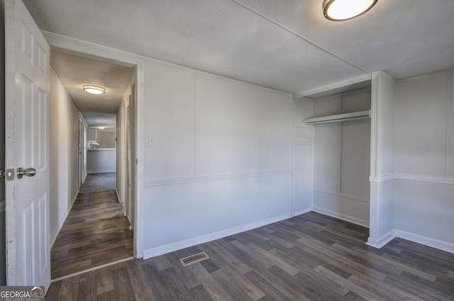 interior space with a textured ceiling and dark hardwood / wood-style flooring