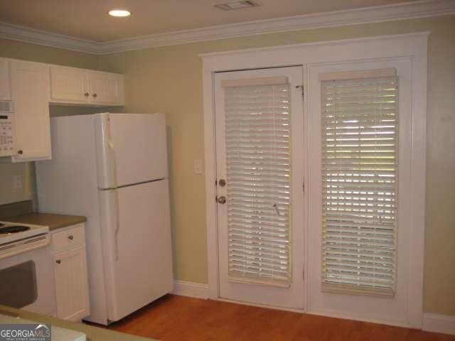 kitchen featuring crown molding, light hardwood / wood-style flooring, white cabinets, and white appliances