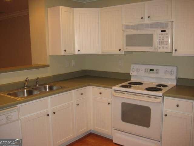 kitchen featuring white cabinetry, sink, crown molding, and white appliances