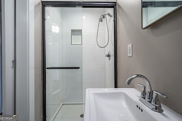 bathroom featuring a shower with shower door and sink