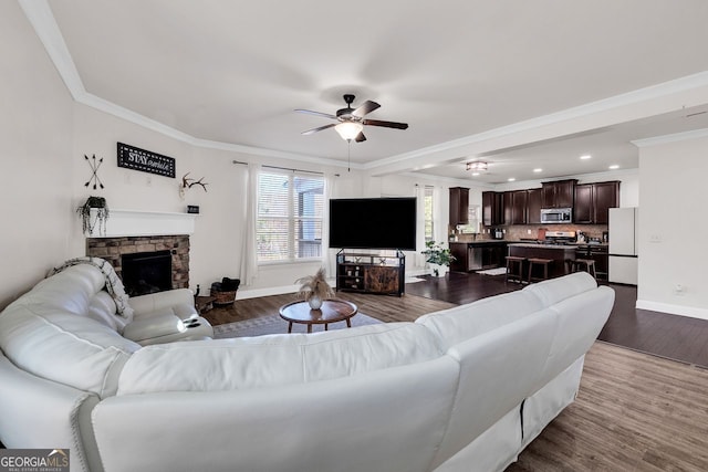 living room featuring a fireplace, hardwood / wood-style floors, ceiling fan, and ornamental molding