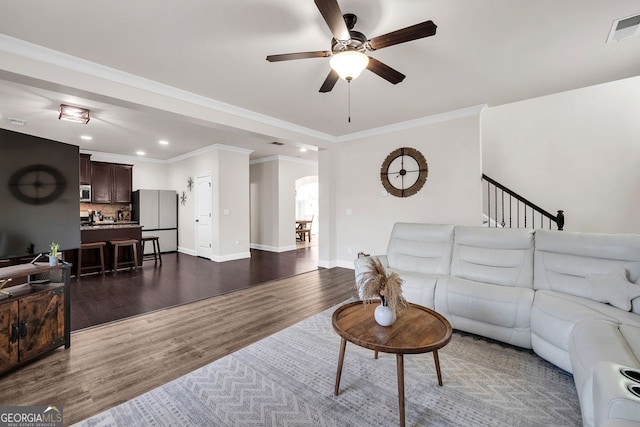 living room featuring dark hardwood / wood-style floors, ceiling fan, and ornamental molding